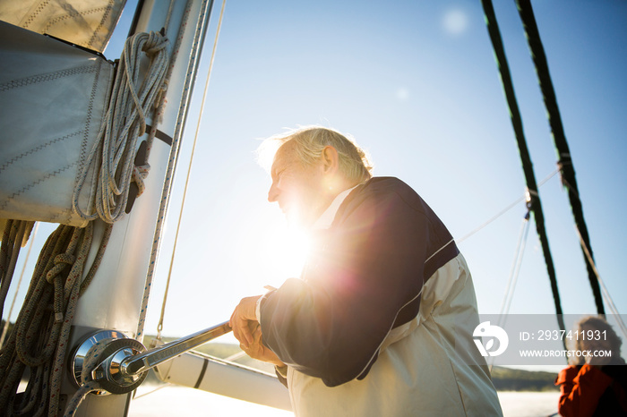 Senior man turning winch at sailboat