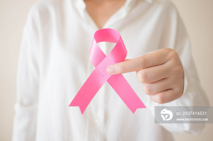 10月乳腺癌症宣传月。白色衬衫女性拿着粉红色缎带的特写