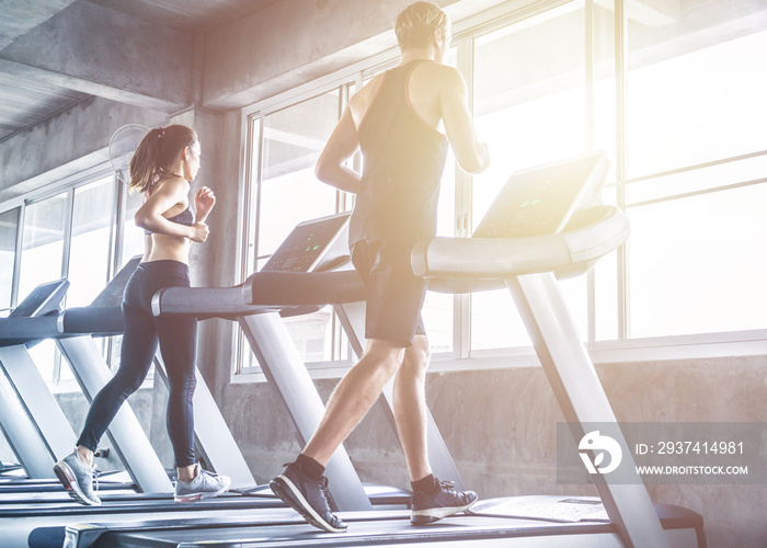 两个穿着运动服的人在跑步机上跑步。慢跑锻炼健身房有氧运动概念。