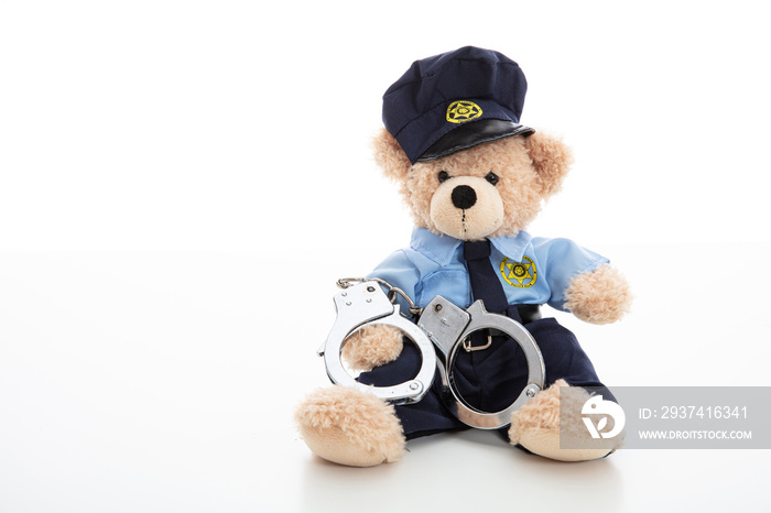 穿着警察制服、戴着手铐的可爱泰迪熊被隔离在白色背景下