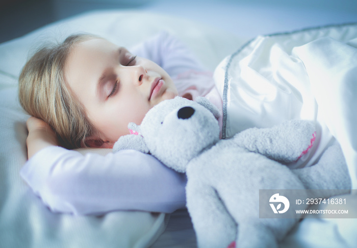 小女孩抱着玩具泰迪熊睡在床上