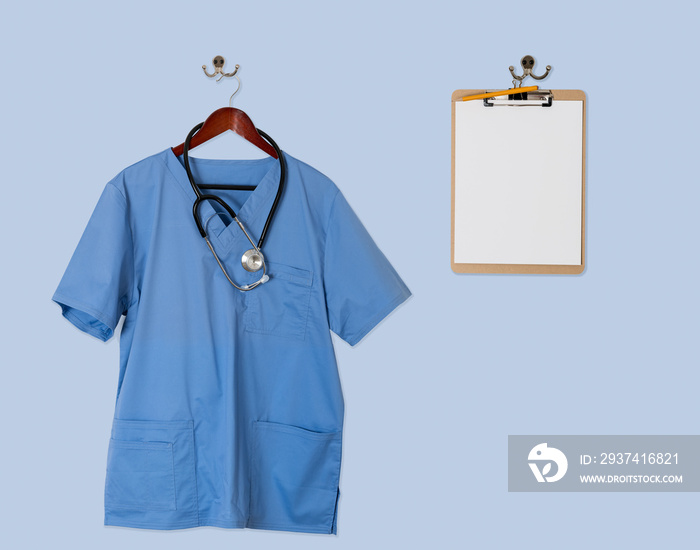 Blue scrubs shirt for medical professional hanging with clipboar