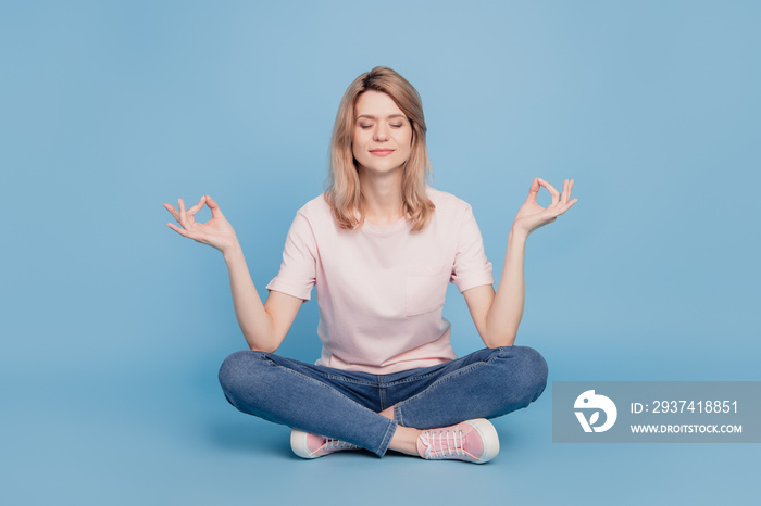 Portrait of peaceful dreamy inspired girl sit floor meditate close eyes on blue background