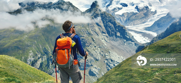 hiker on the trail in the Apls mountains. Trek near Matterhorn mount. Mountain ridge on the backgrou