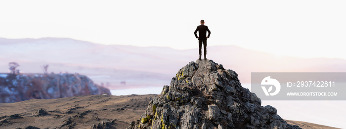 Vision concept, Successful businessman standing top peak mountain with sunset sky and looking forwar