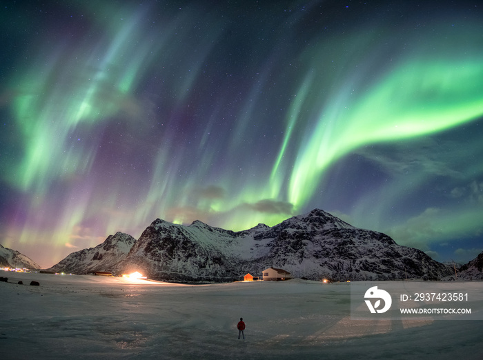 Fantastic Aurora borealis over snowy mountain with man standing