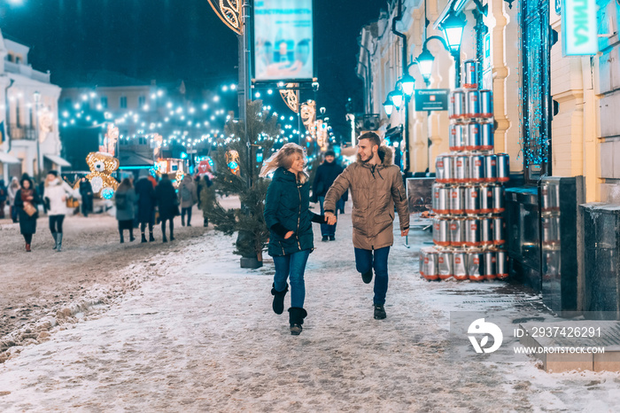 年轻的成年夫妇走在白雪覆盖的人行道上