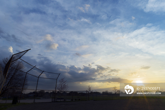 Silhouette of baseball diamond fence at dawn, beautiful sunrise sky with space for text