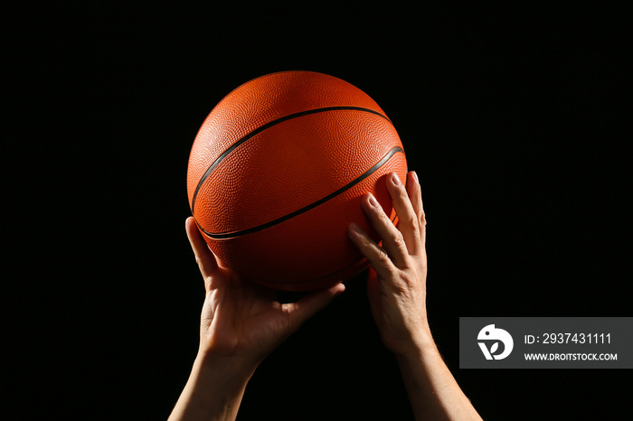 篮球运动员的手在黑暗背景下拿球