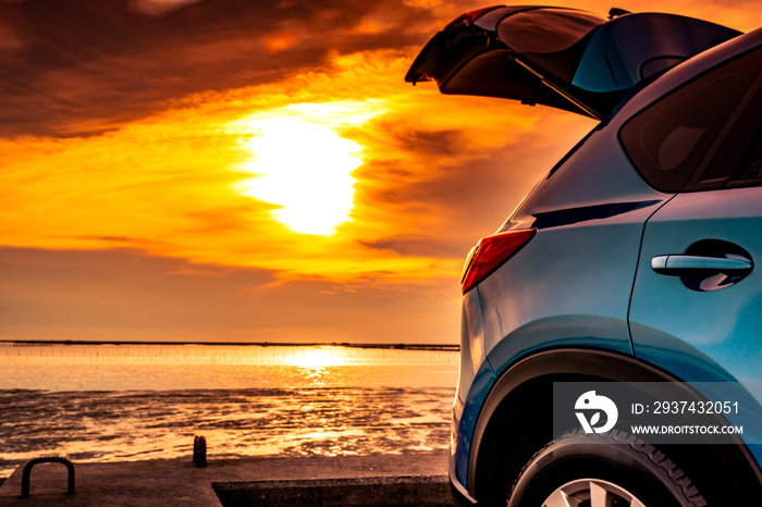 Blue compact SUV car with sport and modern design parked on concrete road by the sea at sunset. Envi