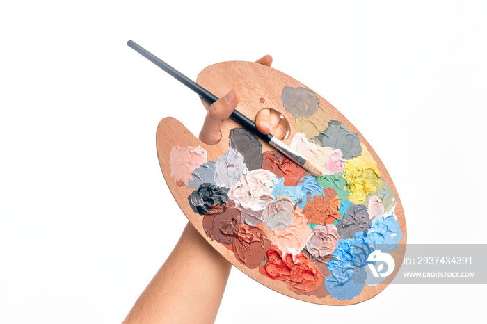 Hand of caucasian young man holding paintbrush and palette with colors over isolated white backgroun