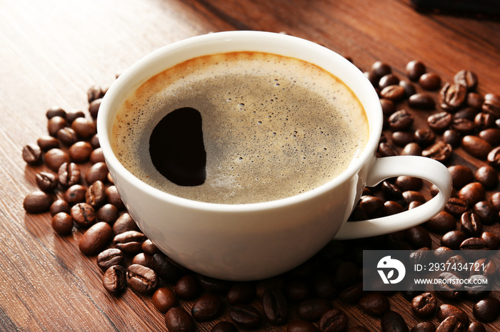 Cup of fresh coffee with beans on table, closeup