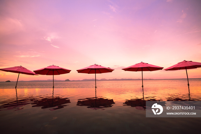 row of umbrella reflected in swimming pool next to beach in twilight, sweet color tone, vanilla sky 