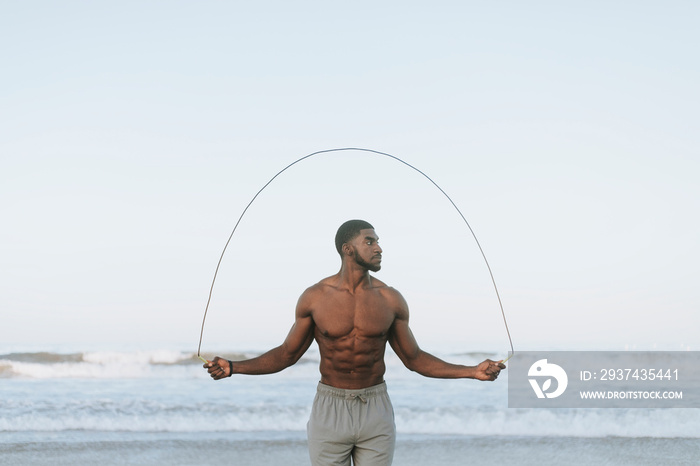 Fit man jumping rope at the beach