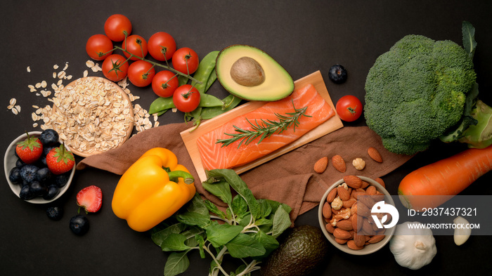 Top view of healthy food assortment with salmon, fruits, vegetable   and seeds on black table