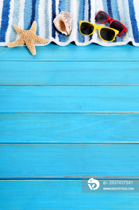 Beach background border striped towel sunglasses and starfish on old weathered blue wood deck deckin