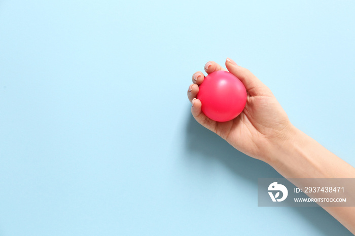 Female hand with stress ball on color background