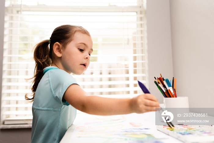 Cute little Caucasian Girl enjoying Painting with water color and art brush. Selective focus.