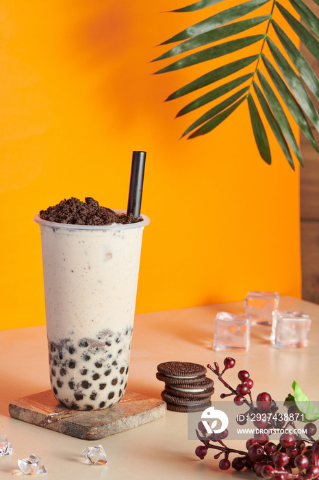 Plastic cup filled with fresh bubble milk tea with crushed cookie chocolate on the top