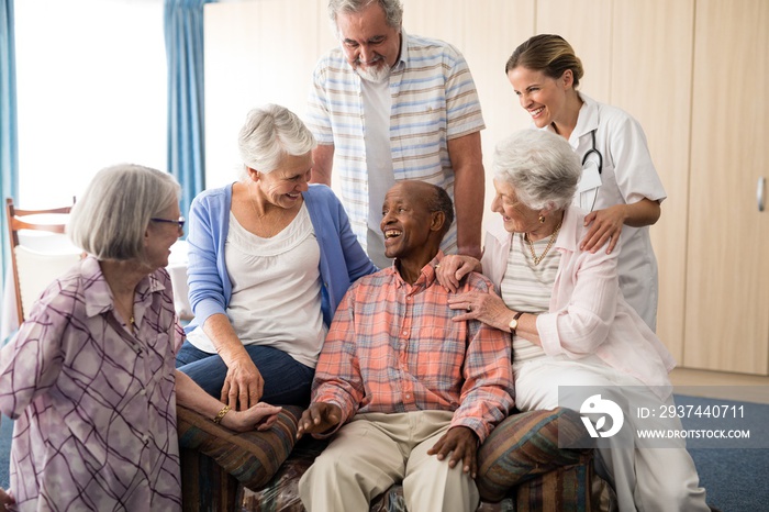 Friends and female doctor looking at cheerful senior man