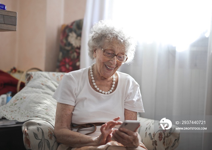 坐在沙发上的老年妇女通过智能手机与家人愉快地交流