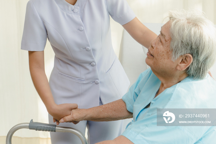 Cheerful asian nurse visiting elderly patient to check up after surgery in hospital for giving physi