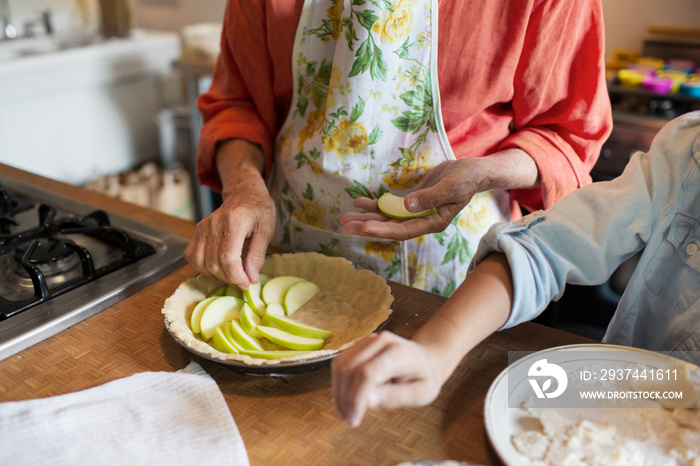 Girl (6-7) making apple pie with grandmother