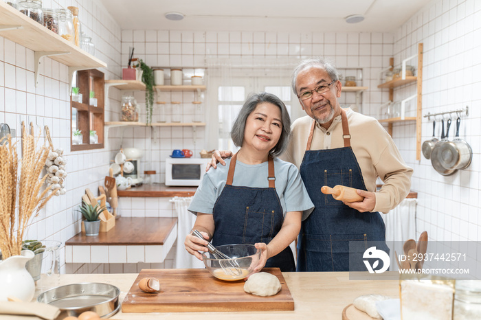 Portrait of Asian senior couple standing in the kitchen cooking bakery