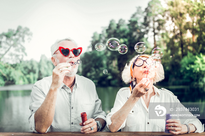 Portrait of man and wife engaging in blowing bubbles outdoors