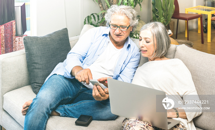 Senior retired couple using laptop computer at home on sofa - Elderly and technology concept with ma