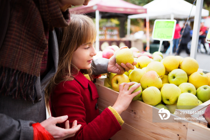 Grandmother with granddaughter (8-9) choosing apples on market