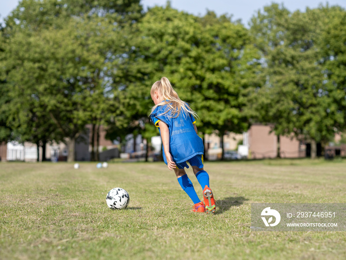 身着制服的女孩（8-9岁）在足球场上练习的后视图