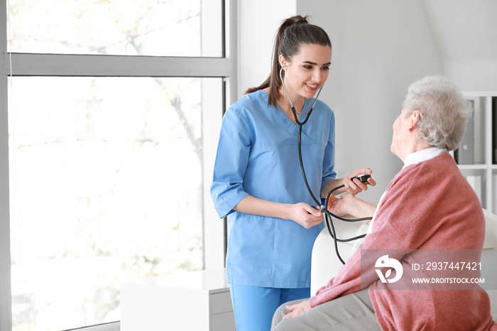 Medical worker examining senior woman in nursing home