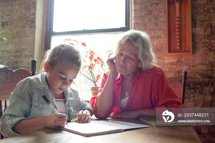 Grandmother doing homework with girl (6-7)