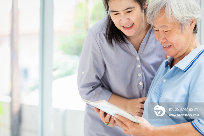 Smiling asian daughter visit the senior mother and watching at photo album,Alzheimer’s disease in el