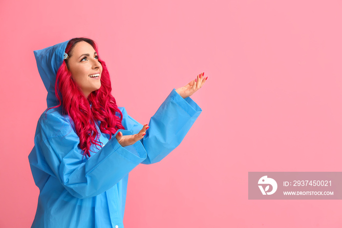 Beautiful woman with bright hair wearing raincoat on color background