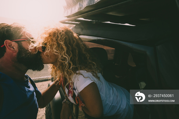 Adult couple in love kiss outside the car and travel together - concept of free and happy lifestyle 