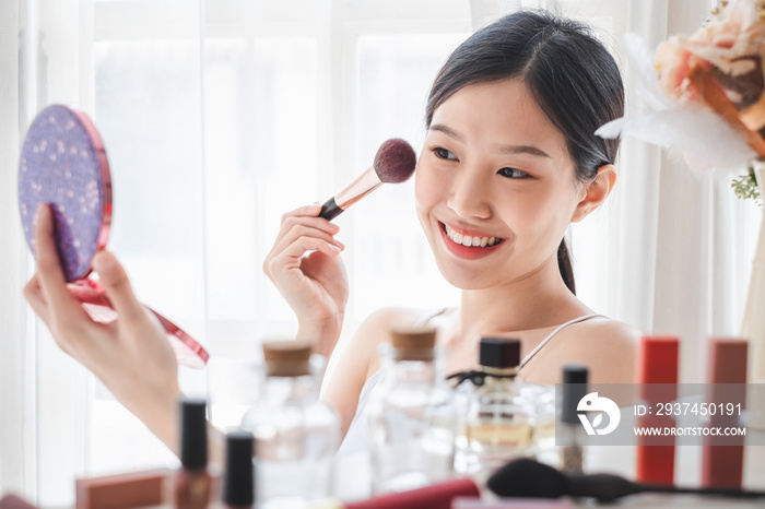 Young beautiful Asian woman applying cosmetics make up on her face, health beauty skin care and make