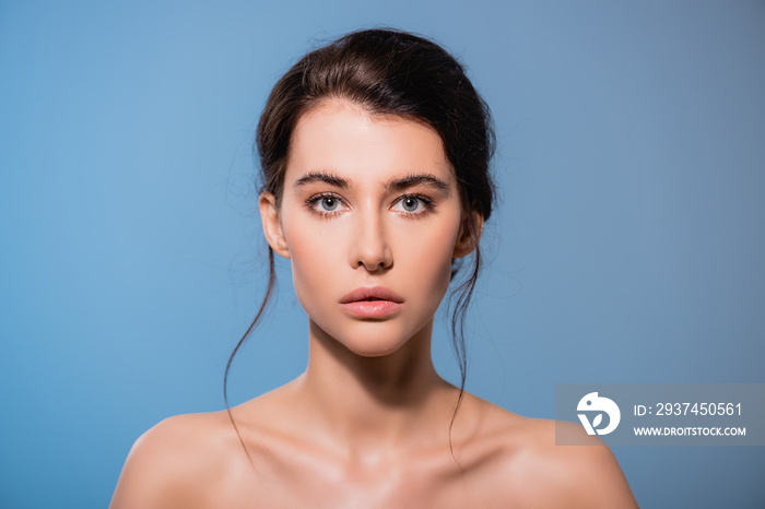 young and naked woman looking at camera isolated on blue