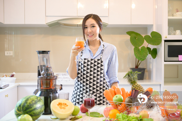 一位美女正在准备健康的新鲜果汁，而蔬菜和榨汁机则放在桌子上。