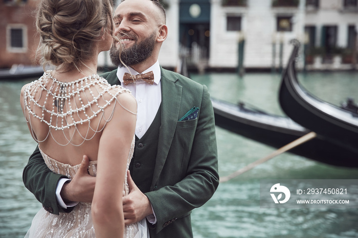 Wedding couple near the canal in Venice. Elegant woman in luxury ivory dress, messy updo hair, man i