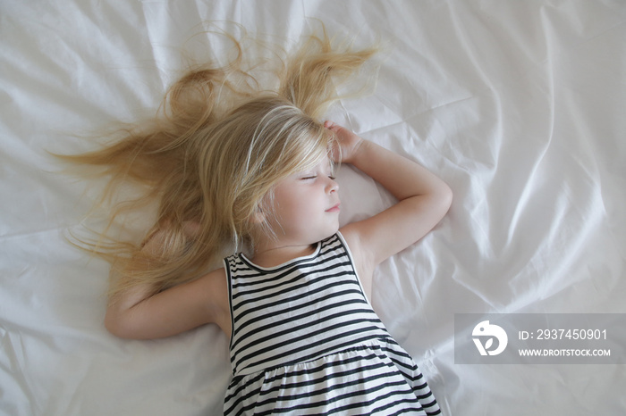 Sweet little girl sleeping in the bed, top view