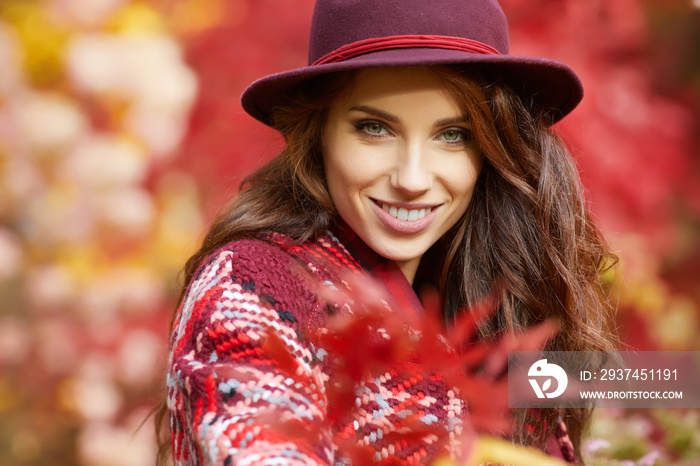 Portrait of an autumn woman over red and golden leaves