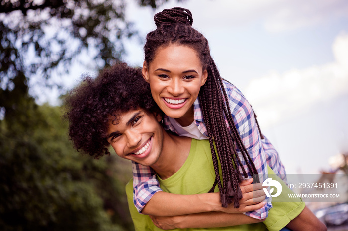 Photo of childish playful boyfriend girlfriend wear casual outfits smiling hugging riding arms outsi