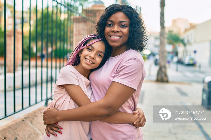 Beautiful african american mother and daughter smiling happy and hugging. Standing with smile on fac