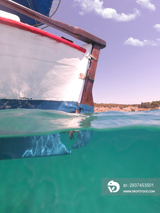 Underwater split photo of traditional wooden fishing boat in Aegean island, with emerald clear sea, 