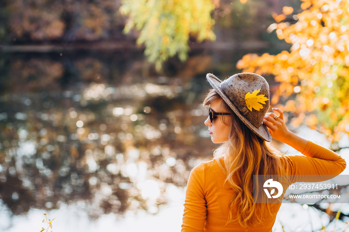 blonde in a yellow jacket on a background of autumn nature. the frame is lit by sunlight. A young wo