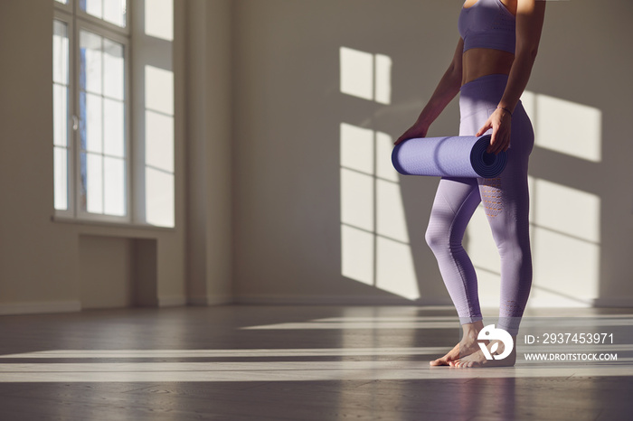 健身瑜伽运动锻炼女性。一个手里拿着瑜伽垫的无脸女性站在一个