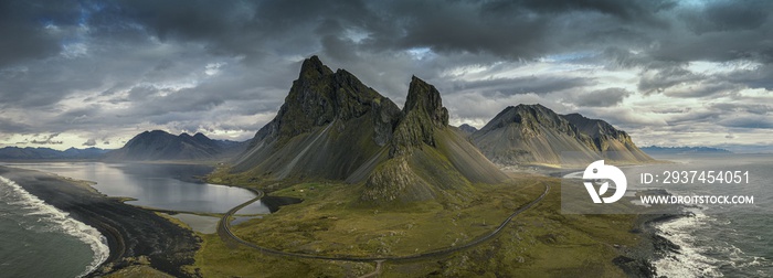 Panoramic shot of hills covered in greenery surrounded by the sea under a cloudy sky