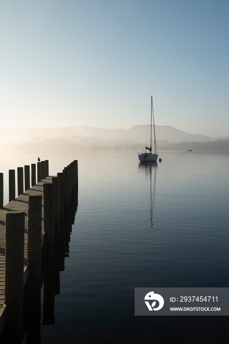 Stunning unplugged fine art landscape image of sailing yacht sitting still in calm lake water in Lak